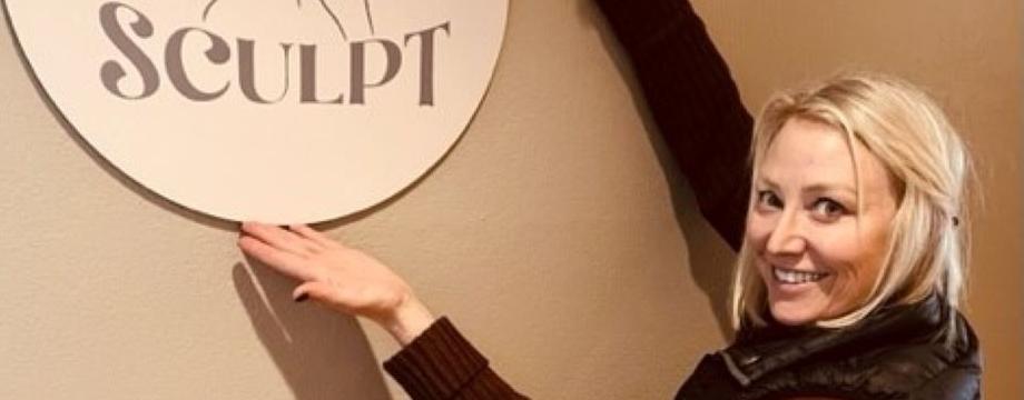 woman pointing to logo for Sculpt hanging on wall